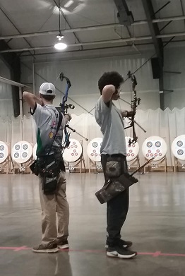 Two 4-H'ers aiming bows in an archery range
