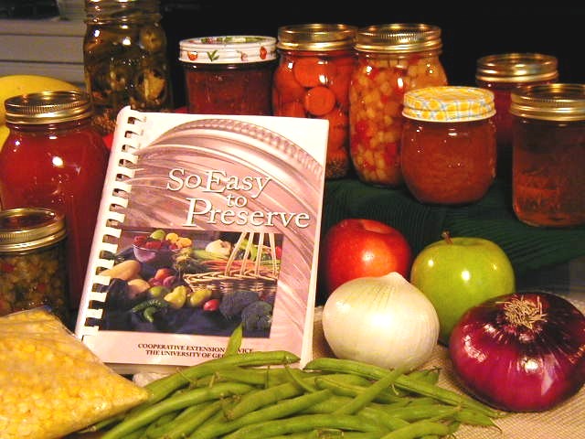So Easy to Preserve book surrounded by vegetables and jarred preserved foods