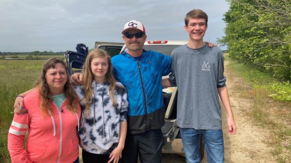Group photo of a family standing beside a truck on a dirt road