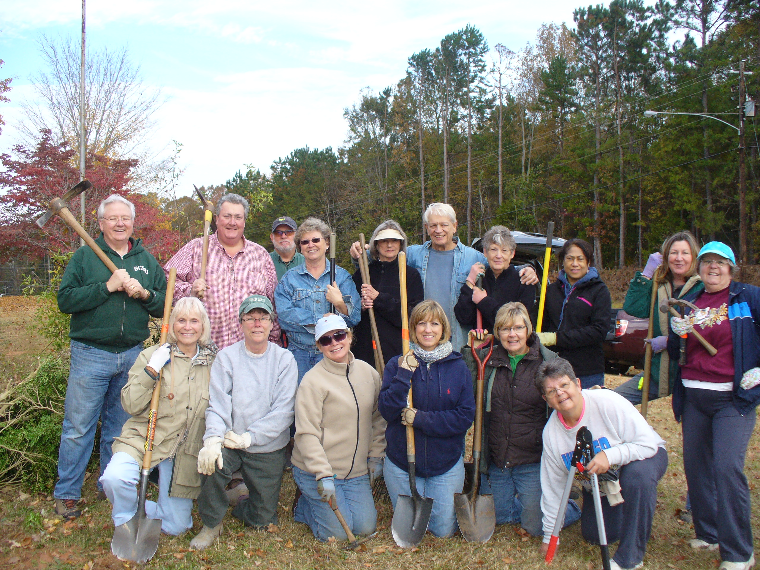 Group photo of Master Gardener volunteers holding shovels and other gardening tools