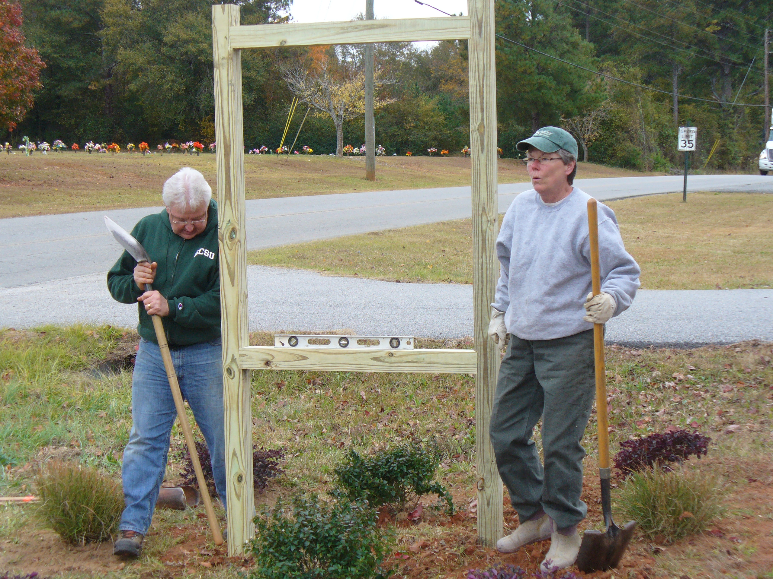 Master Gardener Extension volunteers stand beside a sign frame