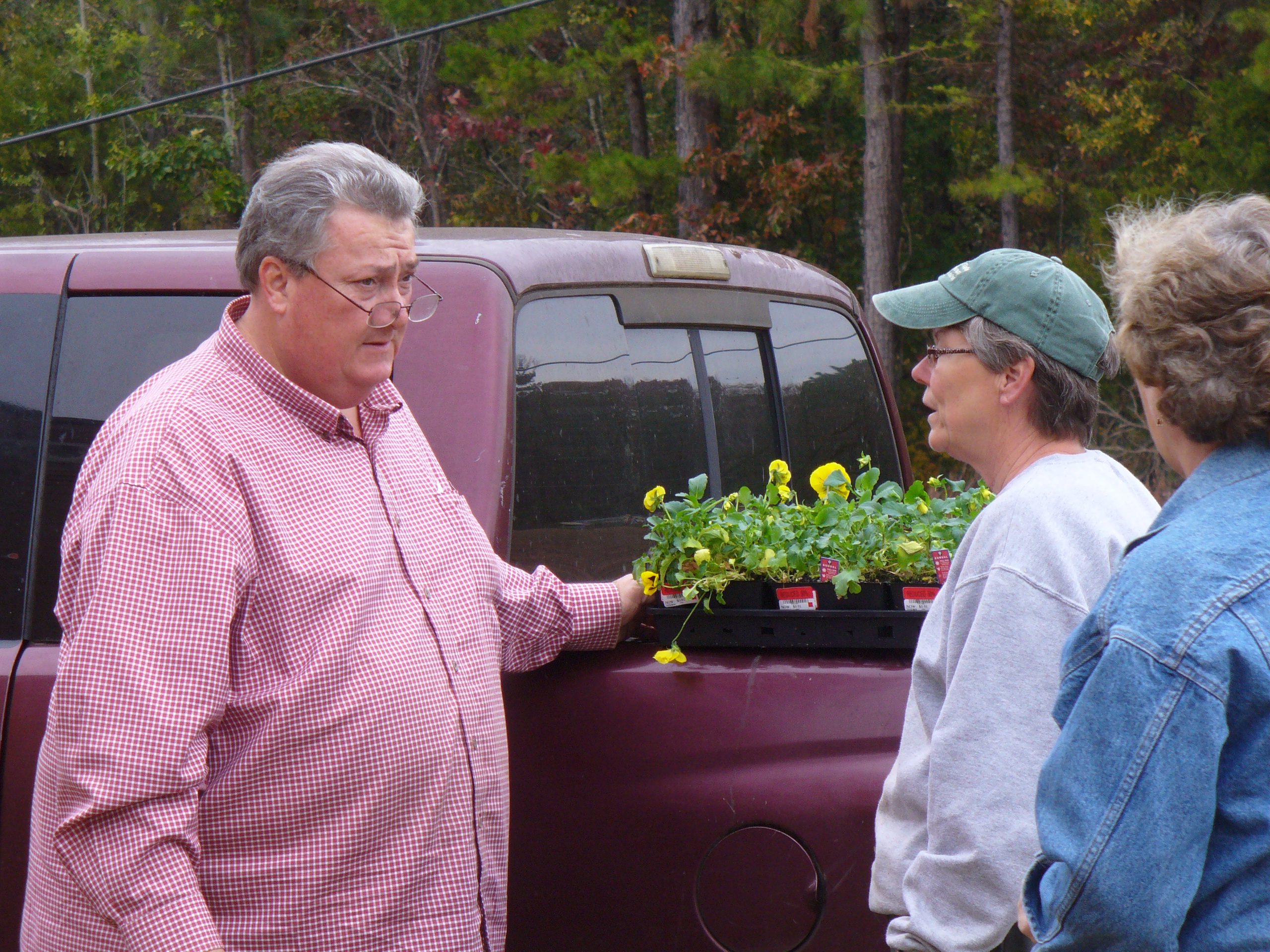 Master Gardener volunteers chat beside a pallet of pansies