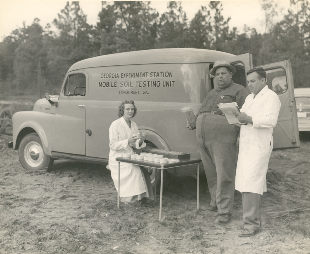 People stand outside a mobile soil testing unit van
